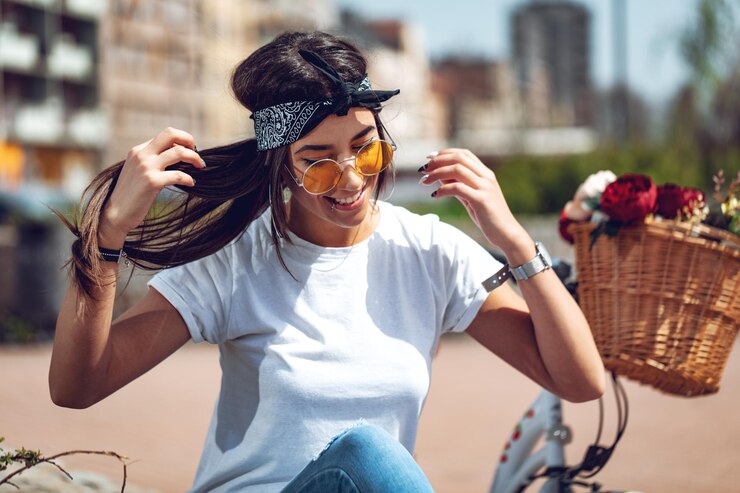 Photo une jeune femme souriante et heureuse profite d'une journée ensoleillée d'été, à côté du vélo avec un panier de fleurs.