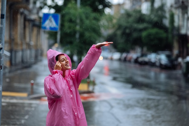 Photo jeune femme souriante avec un imperméable tout en profitant d'un jour de pluie