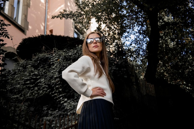 Jeune femme souriante avec des lunettes en sweat à capuche léger à l'extérieur