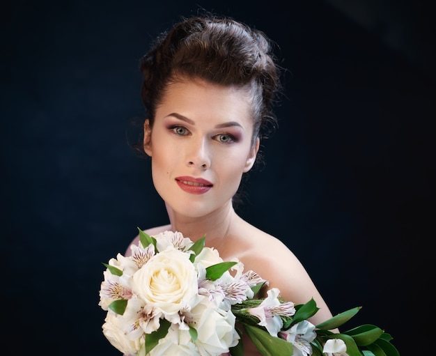 Jeune femme souriante mignonne avec un bouquet de roses et d'orchidées.