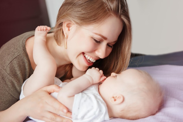 Une jeune femme souriante avec une petite fille dans la chambre à coucher à la maison