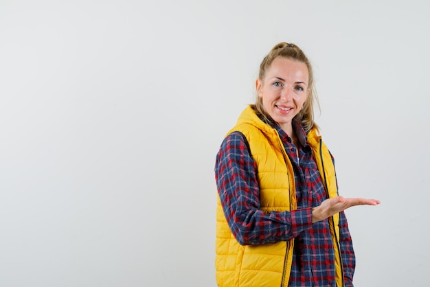 La jeune femme souriante pointe vers la droite avec l'index sur fond blanc