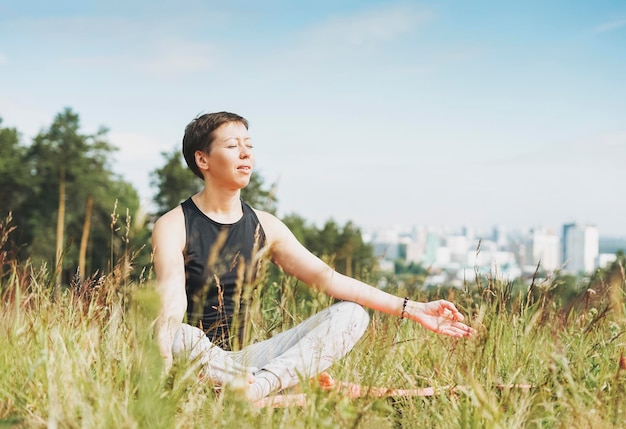 Jeune femme souriante pratique le yoga à l'extérieur dans la ville Nouvelle distance sociale normale Santé physique et mentale