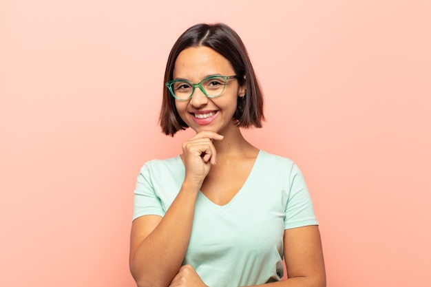 Jeune femme souriante, profiter de la vie, se sentir heureuse, amicale, satisfaite et insouciante avec la main sur le menton