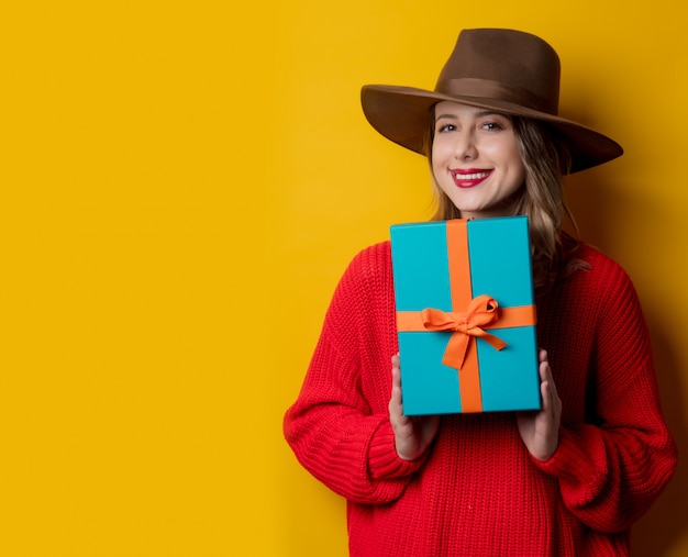 Jeune femme souriante en pull rouge avec boîte-cadeau