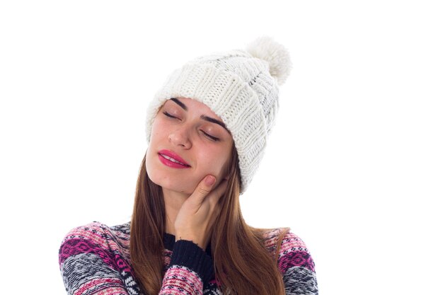 Jeune femme souriante en pull violet et chapeau blanc montrant le poing sur fond blanc en studio