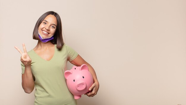 Jeune femme souriante et à la recherche heureuse, insouciante et positive, gesticulant la victoire ou la paix d'une seule main