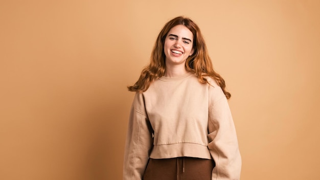 Une jeune femme souriante regardant la caméra dans un studio beige.