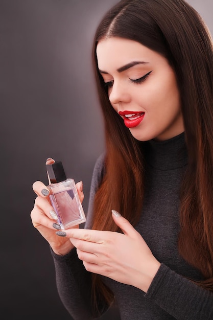 Jeune femme souriante spraing parfums dans la salle de bain