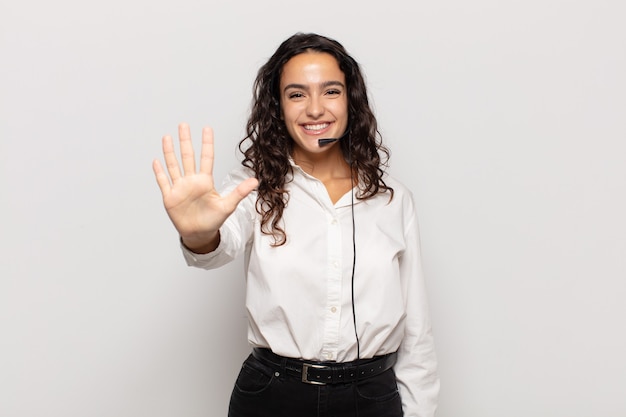 Jeune femme souriante et à la sympathique, montrant le numéro cinq ou cinquième avec la main en avant