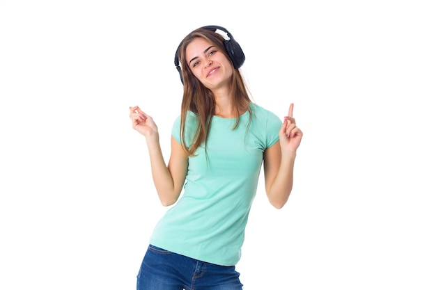 Jeune femme souriante en T-shirt bleu et jeans dans un casque noir sur fond blanc en studio