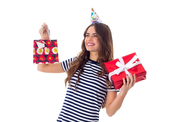 Jeune femme souriante en T-shirt dépouillé et casquette de célébration tenant des cadeaux en studio