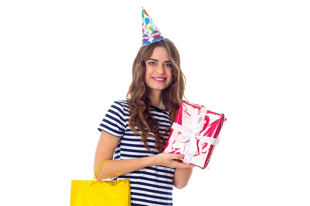 Jeune femme souriante en T-shirt dépouillé et casquette de célébration tenant des cadeaux en studio