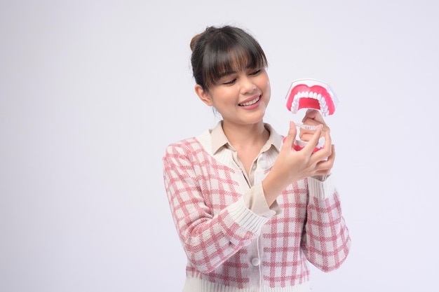 Une jeune femme souriante tenant des accolades invisalign sur fond blanc studio de soins dentaires et d'orthodontie conceptxA