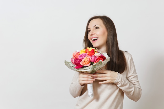 Jeune femme souriante tenant un bouquet de belles fleurs roses isolées sur fond blanc. Copiez l'espace pour la publicité. Avec place pour le texte. Concept de la Saint-Valentin ou de la Journée internationale de la femme