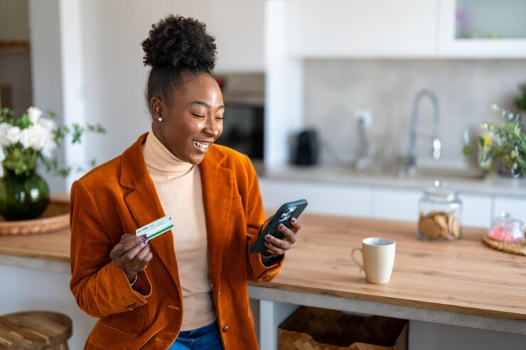 Photo une jeune femme souriante tenant un smartphone en train de regarder sa carte de crédit en utilisant une application de banque en ligne sécurisée par téléphone portable satisfaite d'un achat en ligne avec remboursement ou de bons services bancaires électroniques