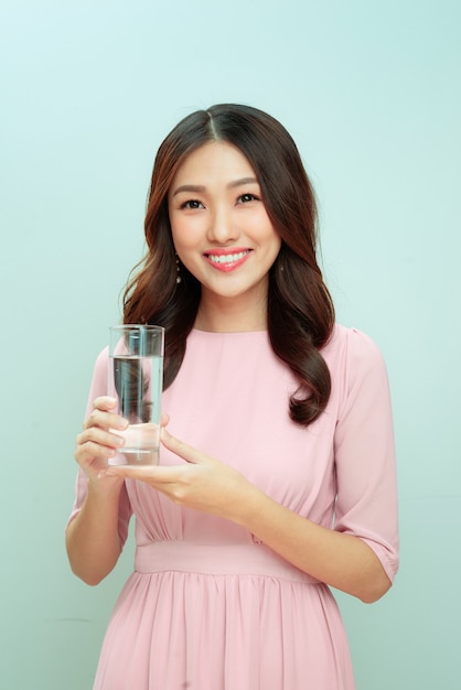 Jeune femme souriante tenant un verre d'eau.