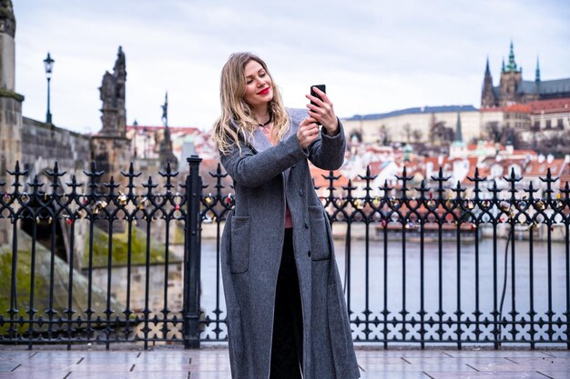 une jeune femme souriante touriste en vêtements de sport marchant dans le centre de Prague avec un téléphone et prenant