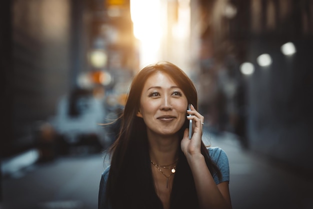 Une jeune femme souriante utilisant un smartphone dans une rue de la ville