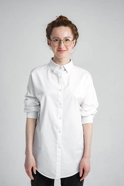 Une jeune femme avec des sourires de taches de rousseur montre ses dents regarde la caméra avec des lunettes blanches