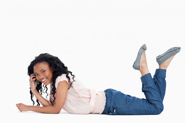 Une jeune femme sourit à la caméra et parle sur son téléphone portable