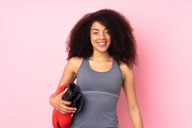 Jeune femme de sport afro-américaine sur mur rose avec des gants de boxe