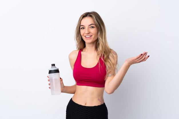 Jeune femme sport sur mur blanc isolé avec bouteille d'eau de sport