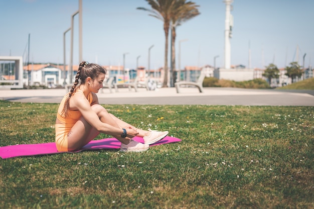 Jeune femme avec un sport orange portant faire du sport dans un jardin public