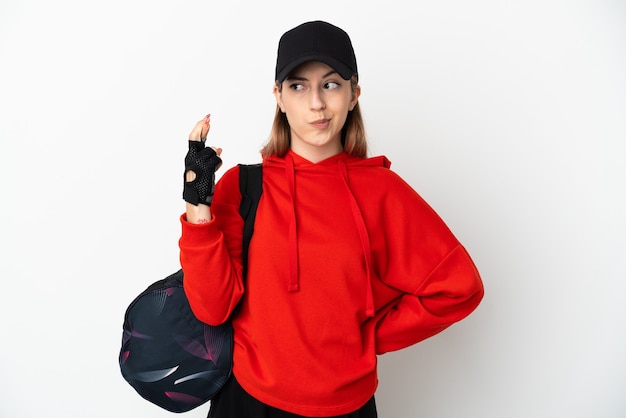 Jeune femme de sport avec sac de sport sur blanc avec les doigts qui se croisent et souhaitant le meilleur