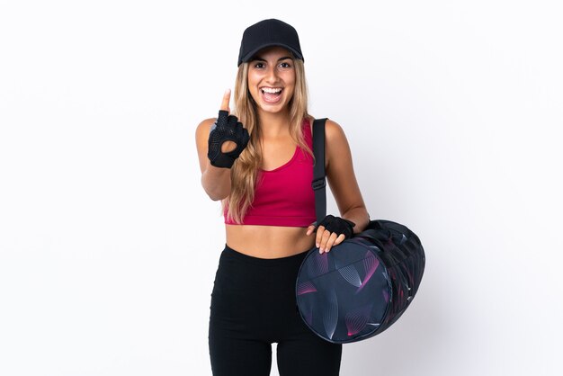 Jeune femme de sport avec sac de sport sur fond blanc isolé faisant le geste à venir