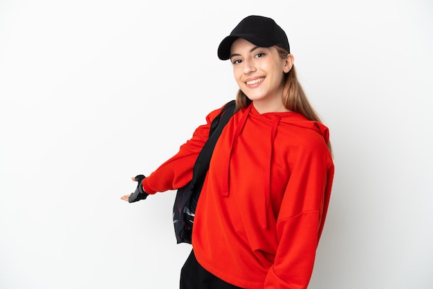 Jeune femme de sport avec sac de sport isolé sur fond blanc étendant les mains sur le côté pour inviter à venir