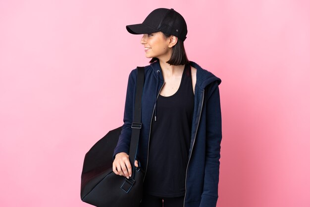 Jeune femme de sport avec sac de sport isolé sur fond rose à côté