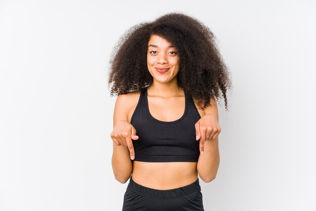 Jeune femme sportive afro-américaine pointe vers le bas avec les doigts, sentiment positif.