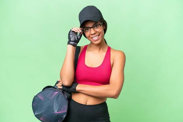 Jeune femme sportive afro-américaine avec un sac de sport sur un fond isolé avec des lunettes et heureuse