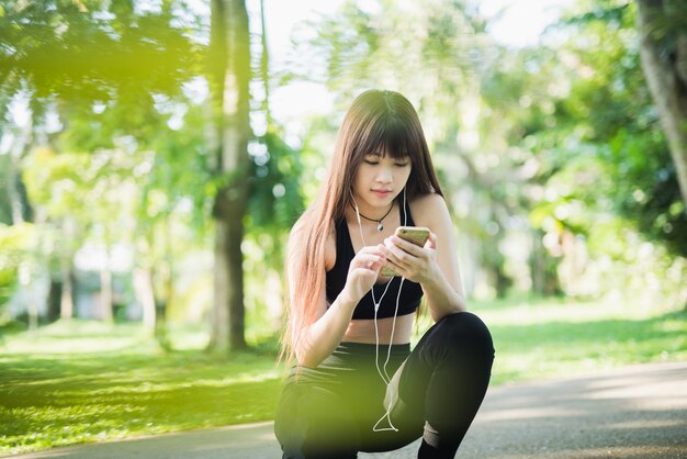 Jeune femme sportive à l&#39;aide de téléphone portable dans le parc