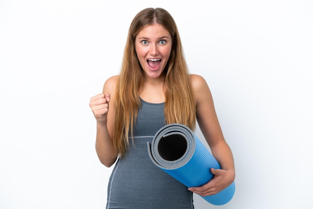 Jeune femme sportive allant à des cours de yoga tout en tenant un tapis célébrant une victoire en position de vainqueur