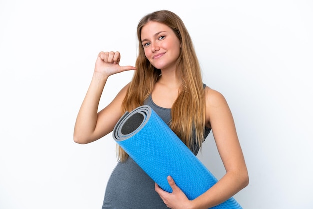 Jeune femme sportive allant à des cours de yoga tout en tenant un tapis fier et satisfait de soi