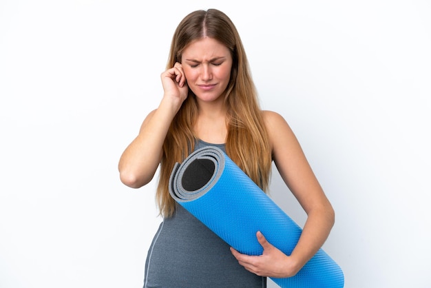 Jeune femme sportive allant à des cours de yoga tout en tenant un tapis frustré et couvrant les oreilles