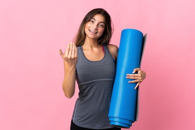 Jeune femme sportive allant à des cours de yoga tout en tenant un tapis isolé