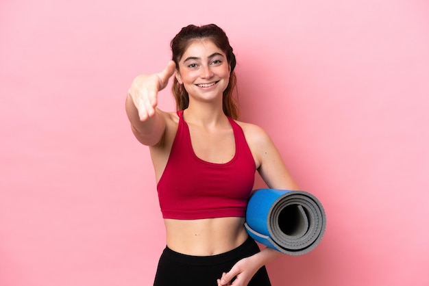 Jeune femme sportive allant à des cours de yoga tout en tenant un tapis se serrant la main pour conclure une bonne affaire