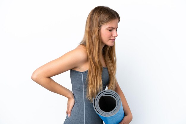 Jeune femme sportive allant à des cours de yoga tout en tenant un tapis souffrant de maux de dos pour avoir fait un effort