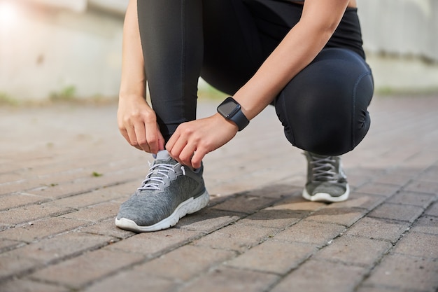 Jeune femme sportive assise tout en ayant un arrêt supplémentaire pendant la course