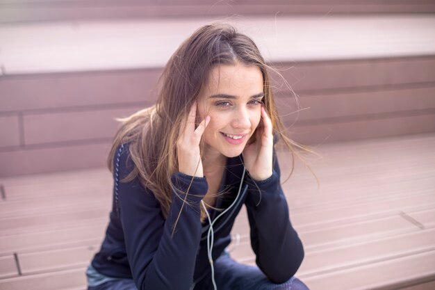 Jeune femme sportive au repos et écouter de la musique sur téléphone mobile après une formation en plein air en milieu urbain