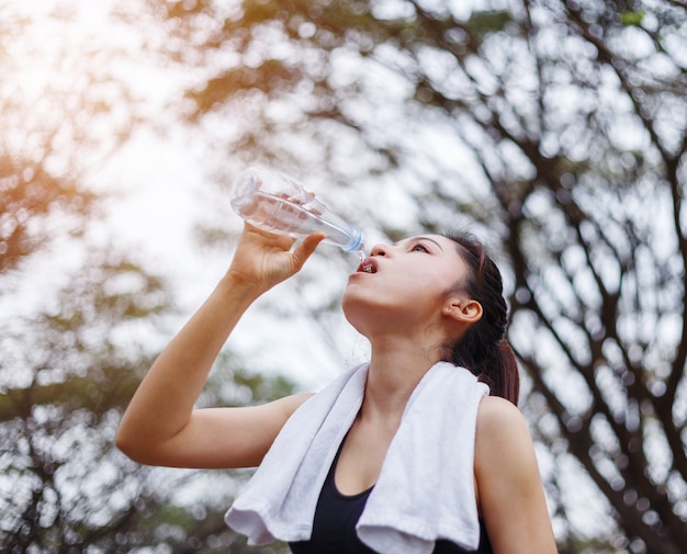 jeune femme sportive, boire de l&#39;eau dans le parc