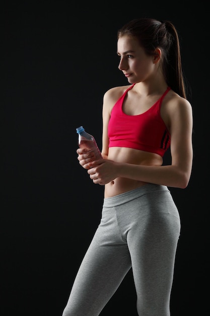 Jeune femme sportive avec une bouteille d'eau fond noir