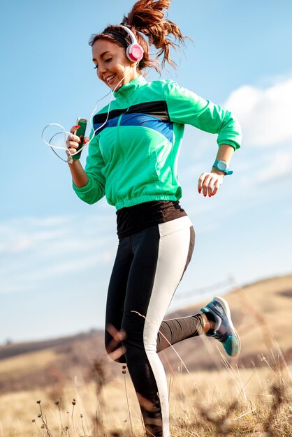 Jeune femme sportive avec un casque de jogging dans la nature.