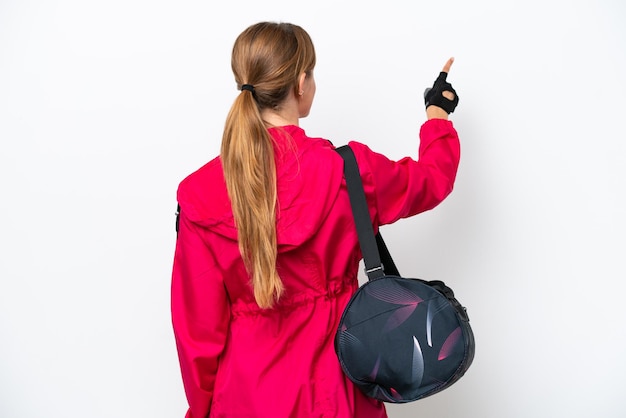 Jeune femme sportive caucasienne isolée sur fond blanc pointant vers l'arrière avec l'index