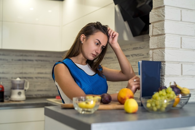 Jeune femme sportive coupant des fruits frais différents sur une table en bois dans la cuisine. nourriture saine