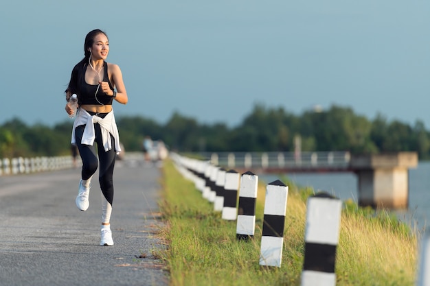 Jeune femme sportive courant sur la route dans la belle nature