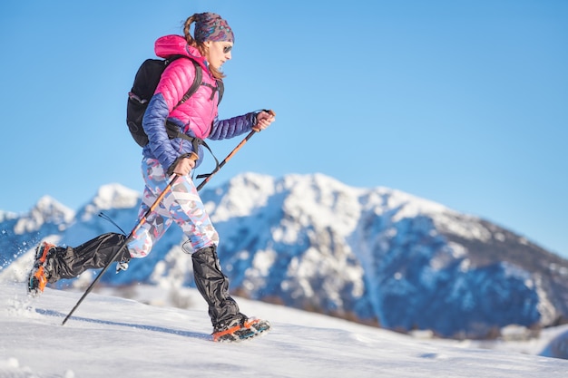 Jeune femme sportive dans la neige avec des crampons et des guêtres